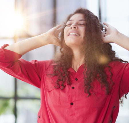 Beautiful smiling young woman in headphones in modern office