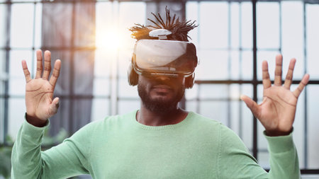 Cool handsome african american man put on virtual reality goggles for the first time in the office.