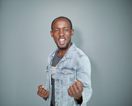 Portrait of a black man with his arms crossed on a gray background.