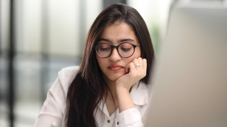 Beautiful portrait of a young woman and female student, while working on her computer or laptop at the office table.の写真素材