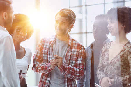 a team of young designers sticking notes on glass in a modern officeの写真素材