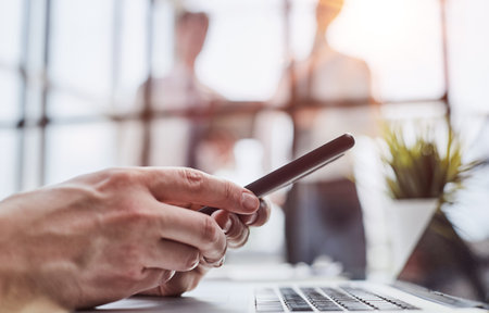 Serious office worker using mobile phone, close-upの写真素材