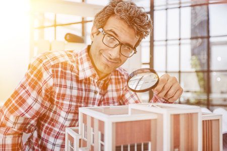 the guy looks at the layout of the house through a magnifying glassの写真素材