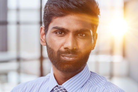 Close up portrait of young attractive serious guy in blue shirt looking straight in the cameraの写真素材