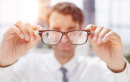 a young man looks at the camera through glassesの写真素材