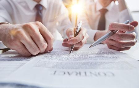 Close-up of businessmen reviewing a close-up contract while sitting at a tableの写真素材