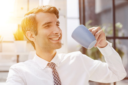 Concentrated businessman holding coffee cup while workingの写真素材
