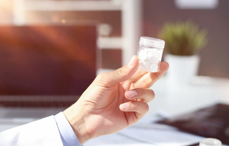 Doctor recommends medicine pill. Practitioner with bottle of pills. hand hold white plastic pill bottle.の写真素材