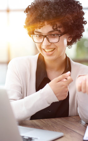 Portrait of Young Successful Caucasian Businesswoman Sitting at Desk Working on Laptopの写真素材