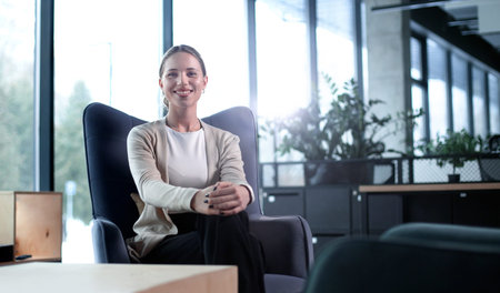 A woman sits in a chair in a room with a potted plant in front of herの写真素材