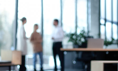 Three people are standing in a room with a potted plant in the backgroundの写真素材