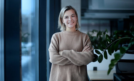 A woman in a brown sweater is looking out the windowの写真素材