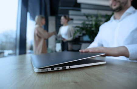 A man is sitting at a desk with a laptop open in front of himの写真素材