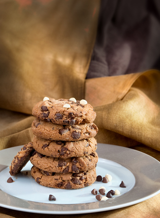 Chocochip cookies tower on yellow-brown batik printed draperyの写真素材
