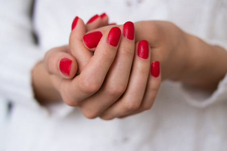 Female hands with red nails on a white background