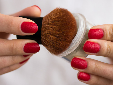 brush and powder in female hands with red nailsの写真素材