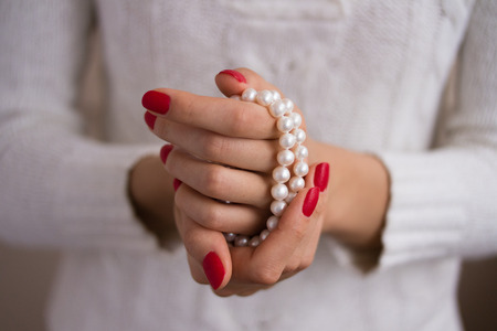 Pearls in female hands with red manicureの写真素材