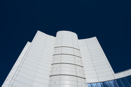 Modern high white business building on a background of blue sky without clouds, contrast image