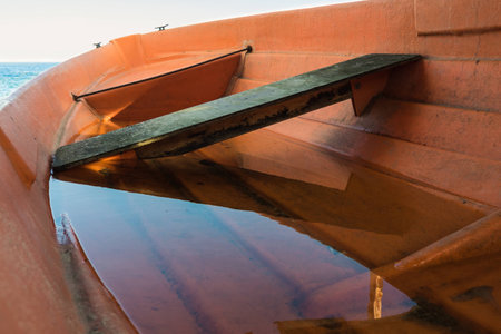 Orange heeled lifeboat filled with water. Overboard see the sea.の写真素材