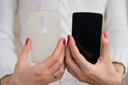 A girl holds in hands with bright red manicure mobile phone and phone caseの写真素材