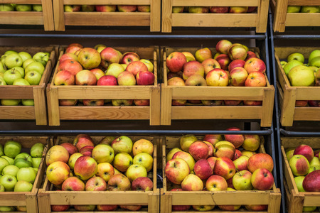Organic apples in wooden boxes in the supermarket are sorted by varietiesの写真素材