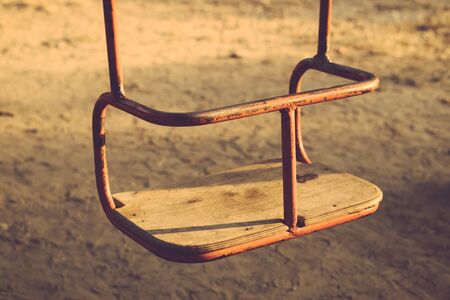 Kids hanging swing rusty metal with wooden seat outdoors. Rear view close-up. Toned image.の写真素材