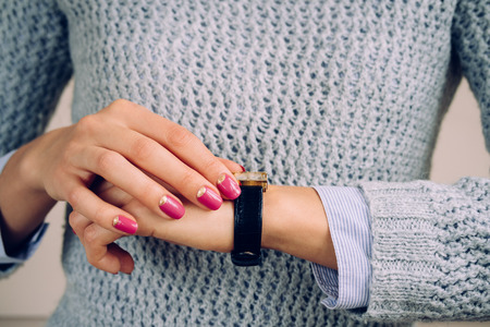 Gold watch with a leather strap on a female hand.の写真素材