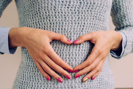 Female hands show heart symbol. Female hand with pink and yellow manicure closeup.の写真素材