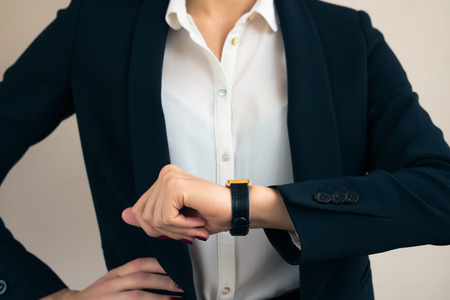 Woman in business suit looks on the hand of the clock close upの写真素材