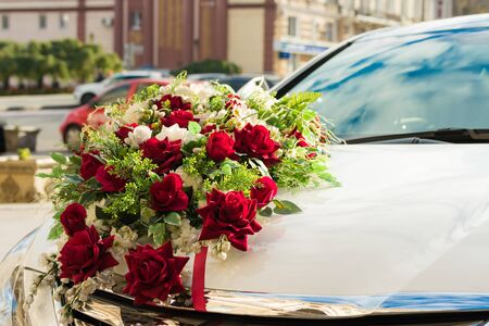 Wedding bouquet on the hood of the white carの写真素材