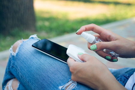 Woman in blue jeans cleans mobile phone antibacterial wipesの写真素材