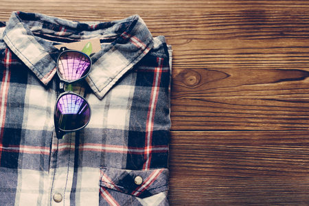 Men's plaid shirt and colored glasses on a wooden background. Top view, copy space.の写真素材