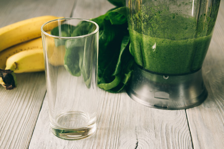 Smoothies in a food processor, glass, banana and spinach on a white wooden backgroundの写真素材