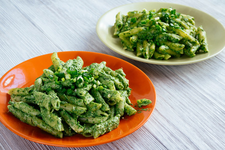 Two plates with spinach pasta on a white wooden tableの写真素材