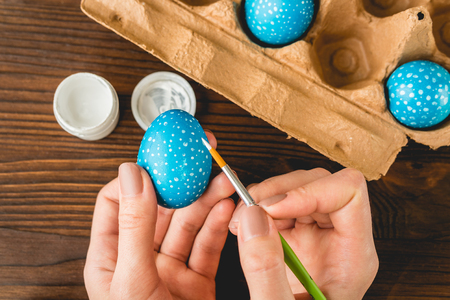 Female hands painted blue Easter eggs with a brush, top viewの写真素材