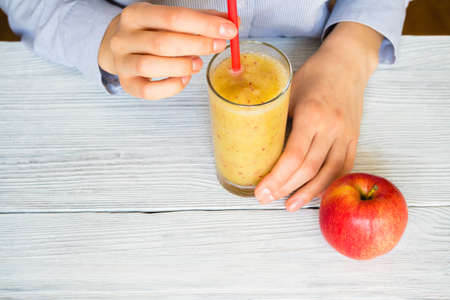 Woman drinks Smoothies from apples and celery in a glass with a straw on a table, top viewの写真素材