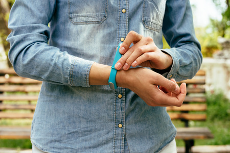 Woman in denim shirt wears sports wristband for measuring stepsの写真素材