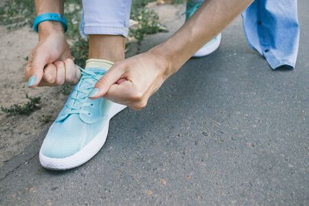 Close-up of girl ties the laces on the shoes while walking around the cityの写真素材