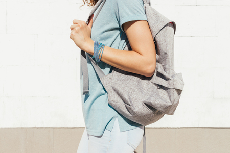 Slender girl with a backpack walking along the city in the summerの写真素材