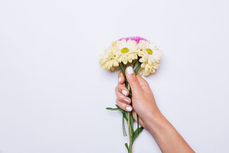 Bouquet of yellow and violet flowers in female hand with white manicure, copy spaceの写真素材