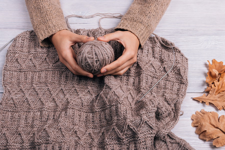 Top view of a woman's hands holding a ball of wool yarn in the background knit sweater, top viewの写真素材