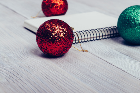 Notebook and Christmas balls on a white table closeupの写真素材