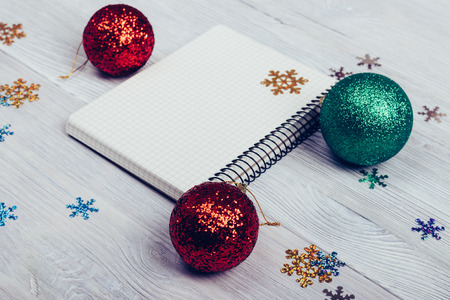 Notepad, Christmas balls and snowflakes on a white table closeup