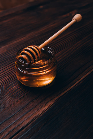 Dipper of honey in a glass jar on the table, vertical framingの写真素材