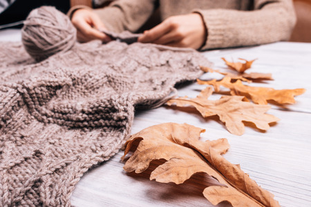 Close up of a woman sitting at the table knitting a wool sweater, a low angle shootingの写真素材