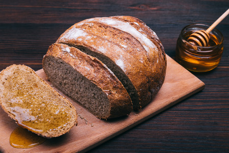 Sliced bread with honey on a brown table closeup