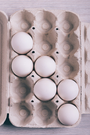 Raw chicken eggs in a tray on the table top view, vertical framingの写真素材