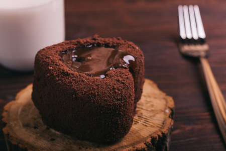 Chocolate cake, a glass of milk and a fork on a table cloth on the table brown, close-upの写真素材