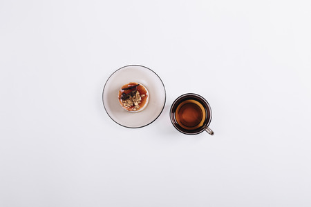 Top view of a cup of tea and cake on the saucer on white tableの写真素材