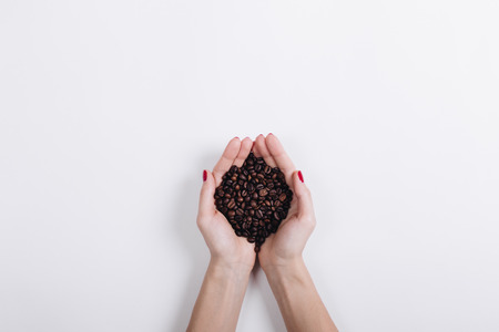 Top view of coffee beans in female hands on a white background, copy spaceの写真素材